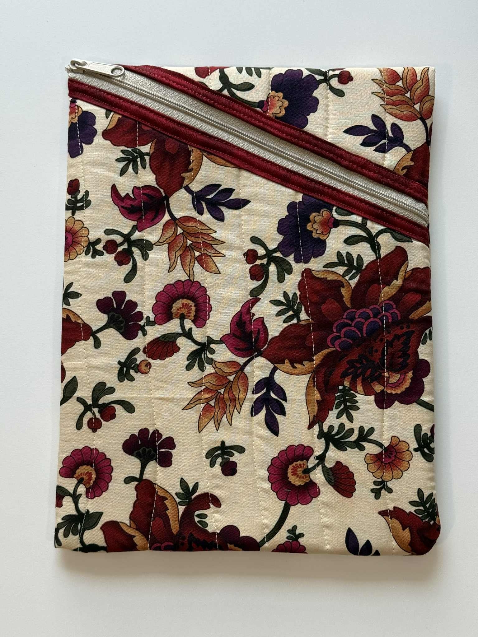 Large quilted diagonal zipper pouch in beige floral fabric with maroon trim